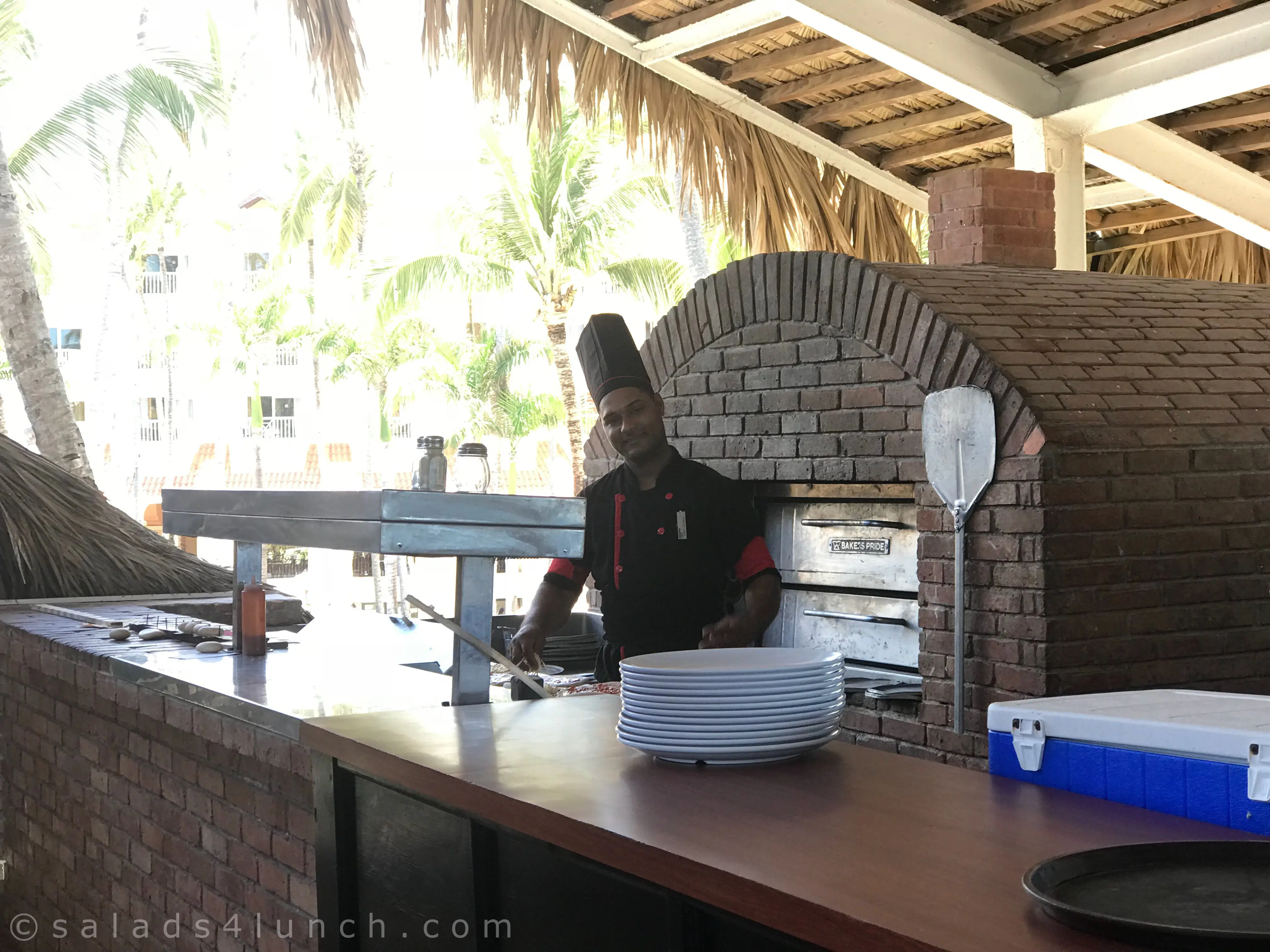 Chef preparing pizza for guests in the outdoor pizza oven.