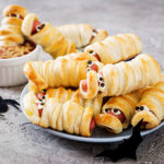 Every Halloween Party needs a silly Mummy – this Mummy Hot Dog Recipe is a fun kitchen food craft for the kids and will be a party favourite. #halloweenrecipe #kidsfoodcraft #foodcraft #halloweentreat #halloweenparty