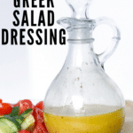 Photo of greek salad dressing in glass jar with tomatoes and cucumbers