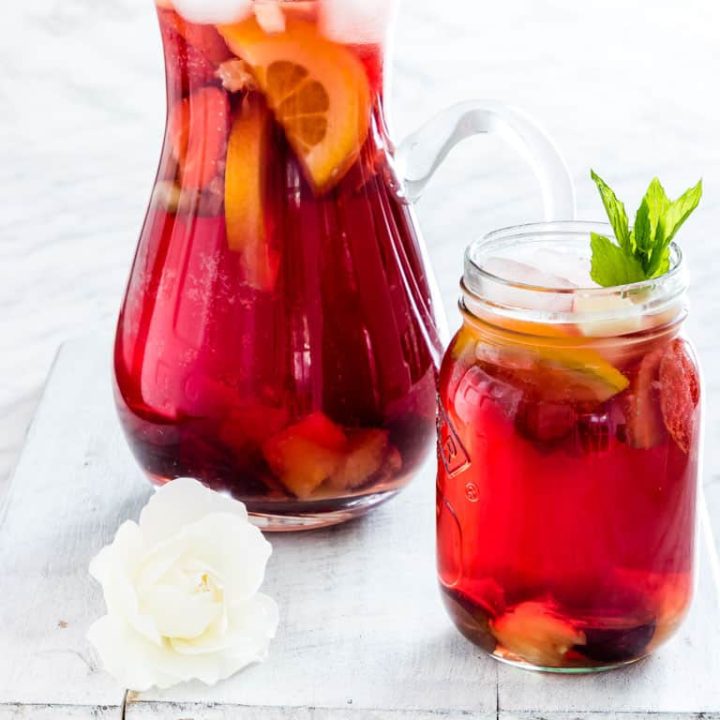 Two glasses of red sangria with sliced lemon in them.