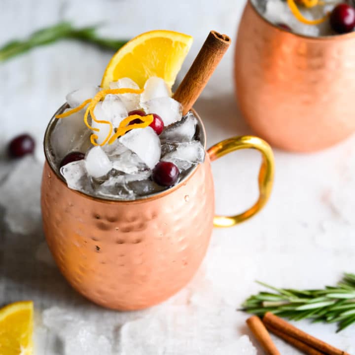 Two cranberry moscow mules in copper mugs.