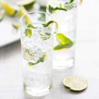 Two classic mojitos in tall glasses with mint.