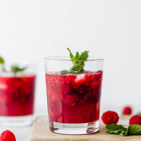 Close up of raspberry mojito with a sprig of mint.