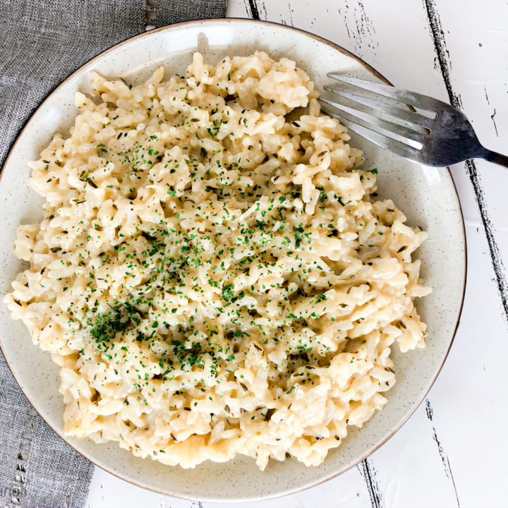 Photo showing close up of plate with Instant Pot Creamy Garlic Parmesan Risotto on a white background with a light grey napkin