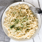 Photo showing close up of plate with Instant Pot Creamy Garlic Parmesan Risotto on a white background with a light grey napkin