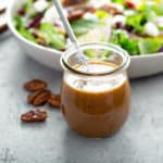 Creamy balsamic vinaigrette dressing in a jar with pecans and salad.