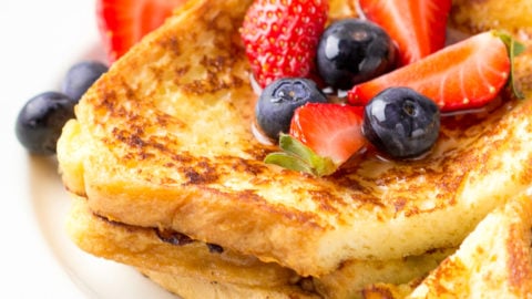 French toast with berries (blueberries, strawberries) and sauce, traditional sweet dessert of bread with egg and milk. Morning baking food.