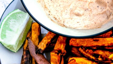 Plate of delicious sweet potato fries made in the air fryer with a bowl of chipotle may in the background