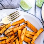 Plate of delicious sweet potato fries made in the air fryer with a bowl of chipotle may in the background