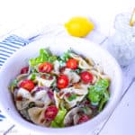 Close up of white bowl on a blue and white striped napkin with a colourful Creamy Ranch BLT Pasta Salad.