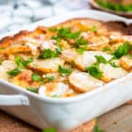 Baked scalloped potatoes garnished with fresh cilantro with text overlay that reads "Easy Creamy Scalloped Potatoes".