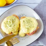 Air Fryer Eggs Benedict with golden hollandaise sauce on a plate.