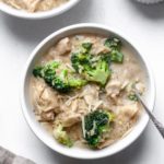 Long photo of chicken broccoli and rice casserole in a white bowl with a tan linen napkin.