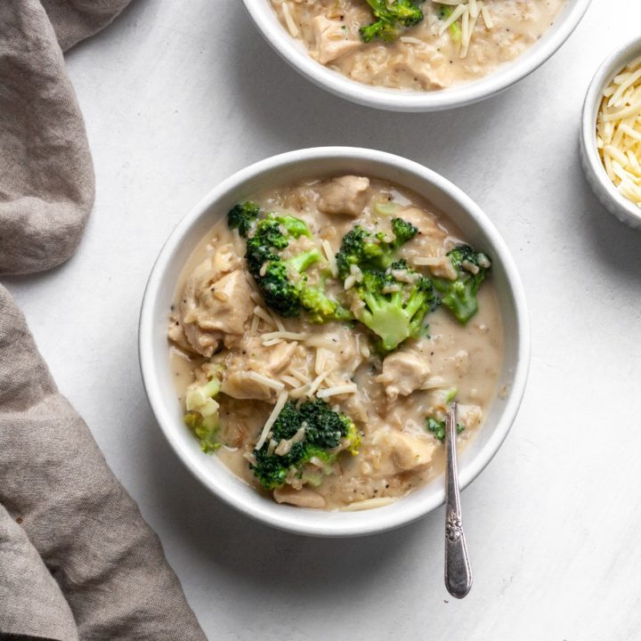 Long photo of chicken broccoli and rice casserole in a white bowl with a tan linen napkin.