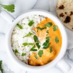 Top view of Indian butter chicken with jasmine rice in a white bowl.