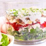 Trifle bowl with EIGHT delicious layers of lettuce, topped with grilled chicken, tomatoes, boiled eggs, homemade dressing, crispy bacon, crumbled blue cheese and green onions.