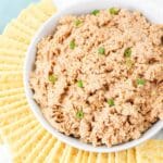 Overhead close up of deviled ham salad in a white bowl garnished with green onion.