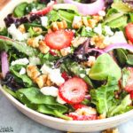 Strawberry feta and mint salad with fresh greens in a white bowl.