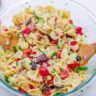 Bow Tie Greek Pasta Salad - Bow Tie Greek Pasta Salad 11 Glass bowl with cucumber, kalamata olives, tomatoes, red onion, feta cheese, parsley, and red bell pepper mixed together with bow tie pasta.