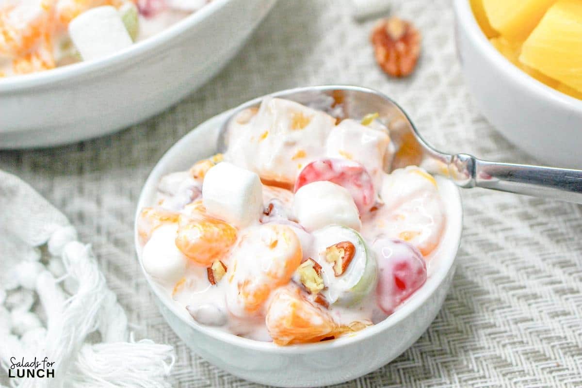 Close-up of Ambrosia Salad without Coconut in a white bowl with a spoon.