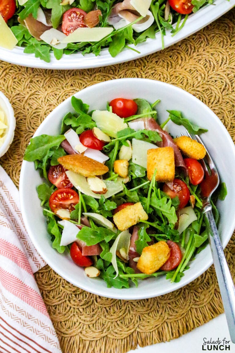 Close up of Arugula and Prosciutto Salad with Lemon Vinaigrette in a white bowl.