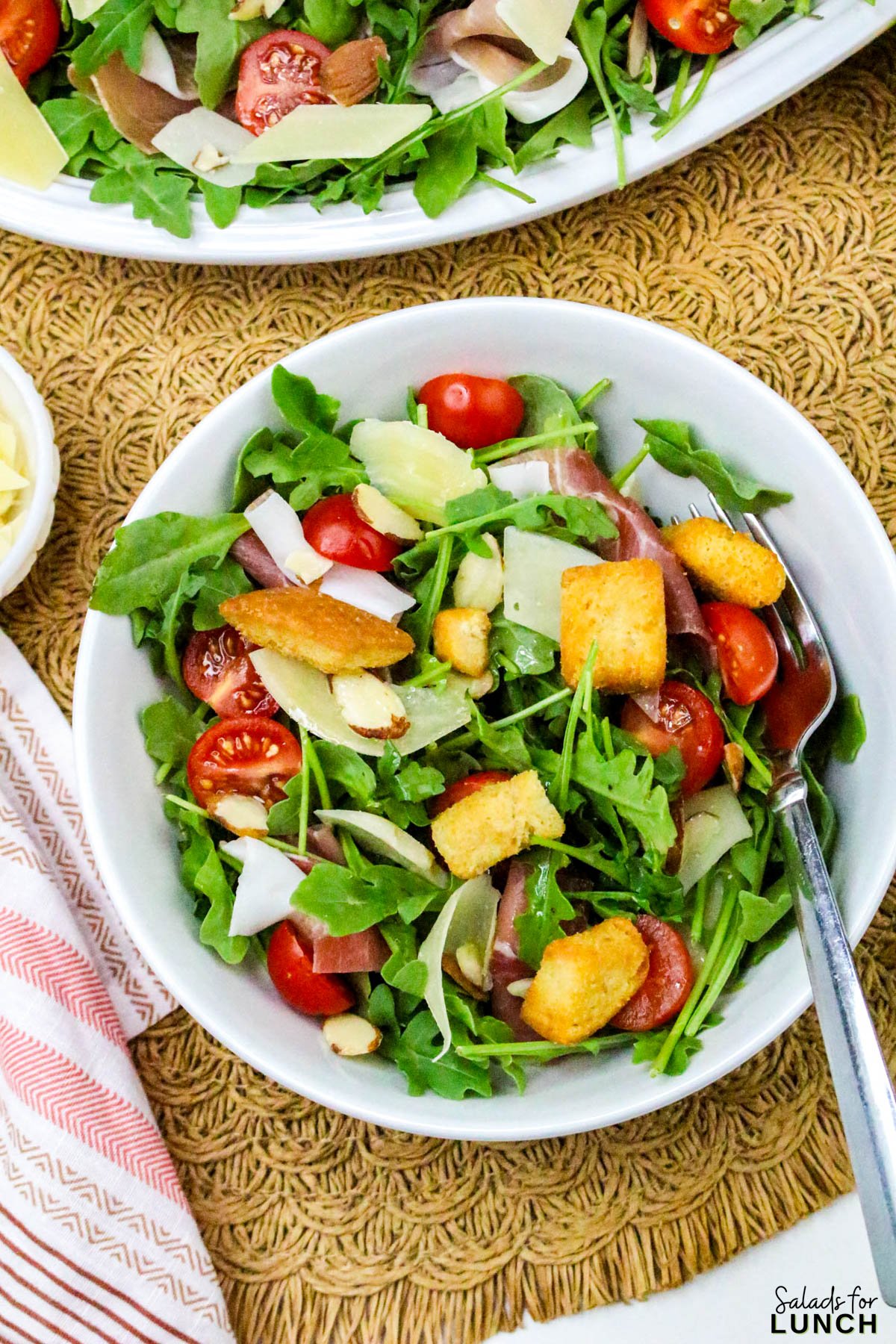 Close up of Arugula and Prosciutto Salad with Lemon Vinaigrette in a white bowl.
