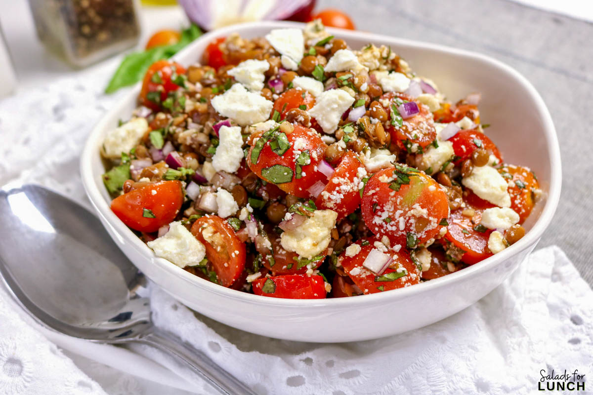 Vegetarian lentil salad with feta and red onion garnished with fresh herbs.