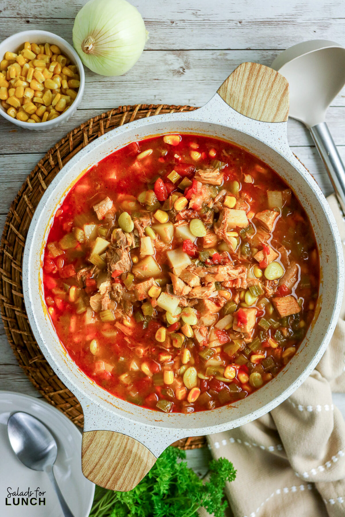 Hearty Brunswick stew in a pot, featuring chicken, pork, corn, and vegetables.