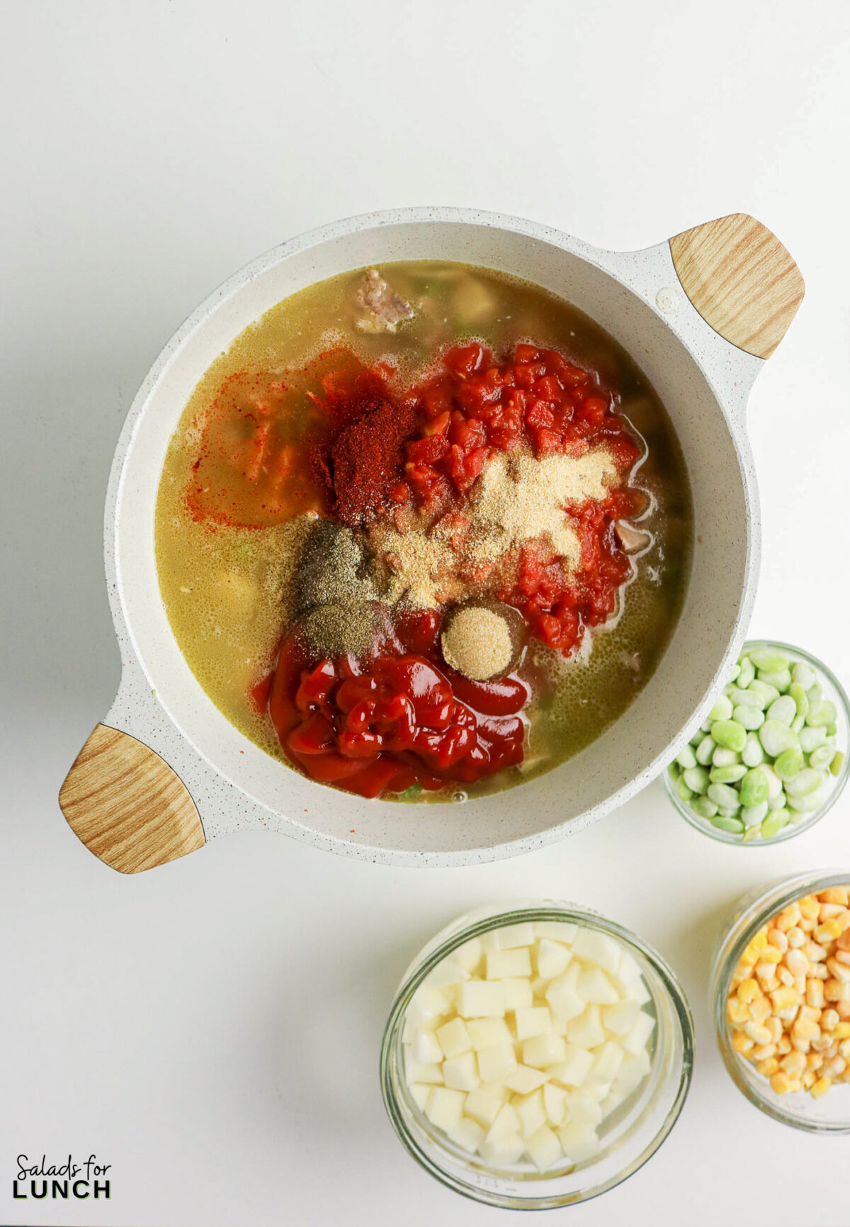 Brunswick stew ingredients in a pot: tomatoes, spices, broth, lima beans, corn, potatoes.