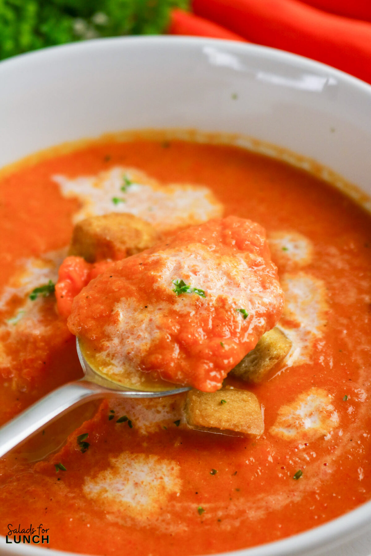 Spoonful of creamy carrot soup with croutons and a swirl of cream. Healthy creamy carrot soup from scratch.