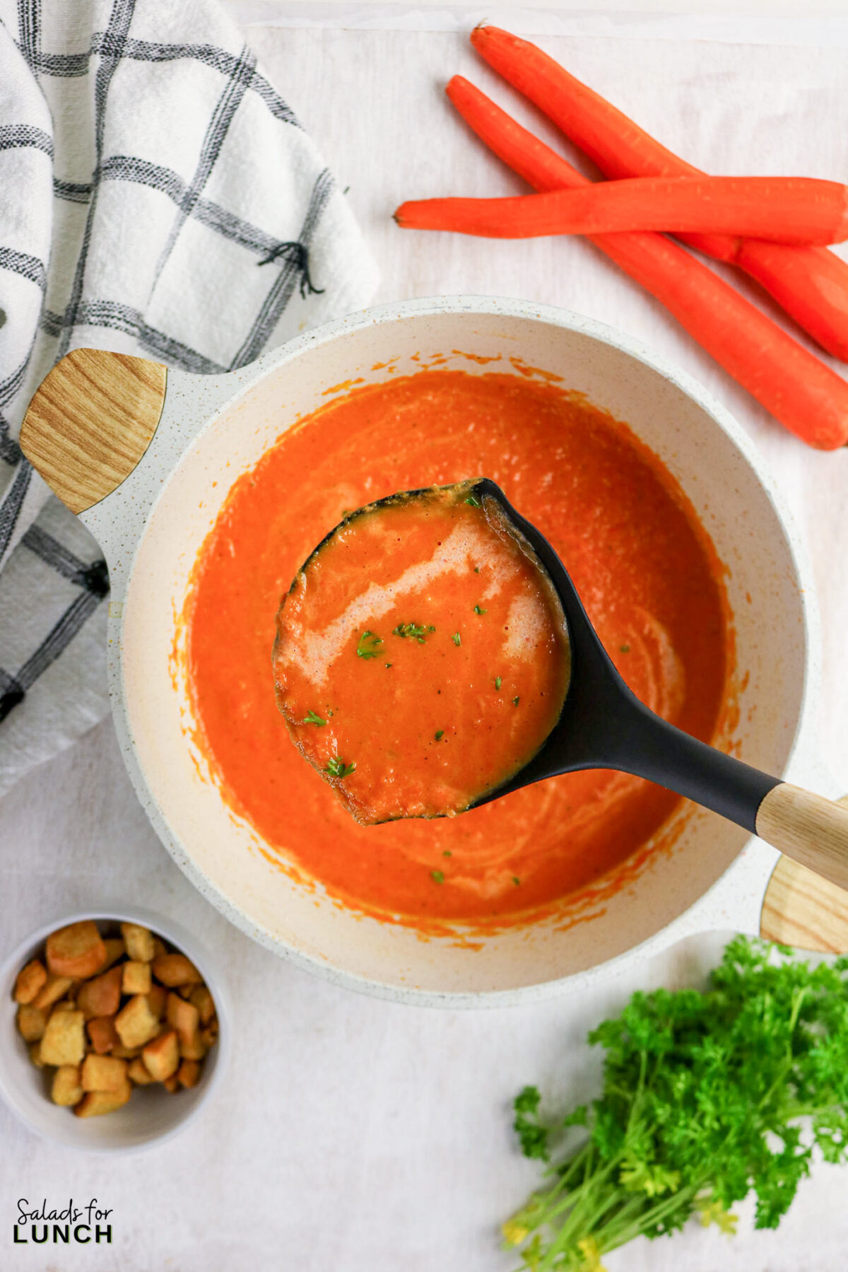 Creamy carrot soup in a pot, ladle scooping some out. Healthy, easy recipe from scratch.