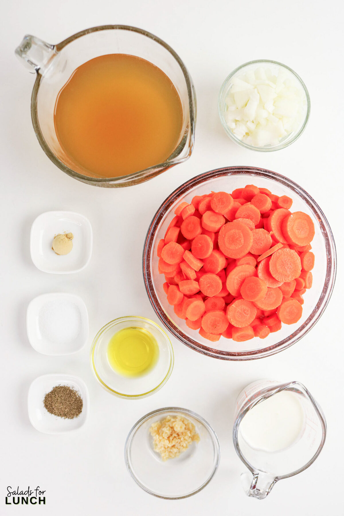 Ingredients for easy creamy carrot soup recipe: carrots, broth, onion, garlic, cream, oil, and spices, ready to cook.