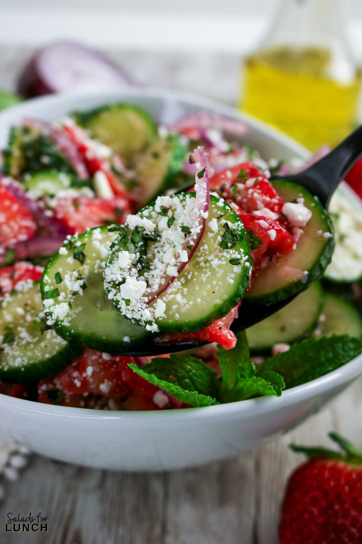 Close-up of Strawberry Cucumber Salad with Feta and Mint on a spoon.