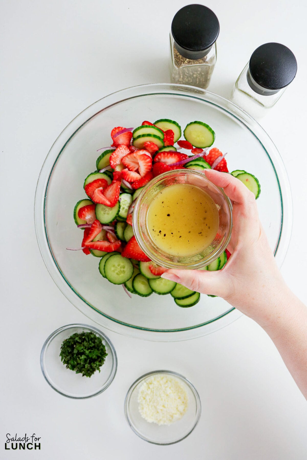 Adding dressing to Strawberry Cucumber Salad with Feta and Mint.