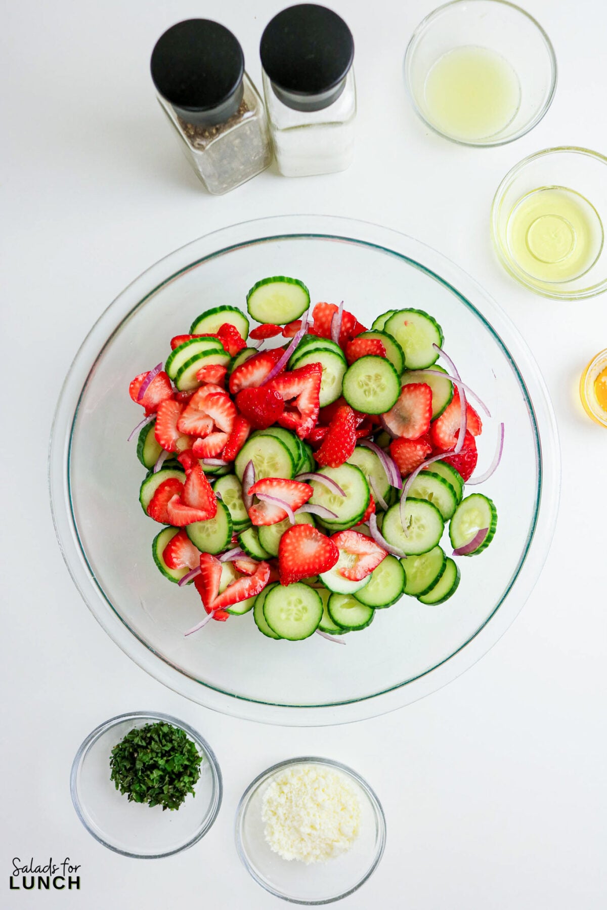 Overhead view of Strawberry Cucumber Salad with Feta and Mint ingredients in bowls.