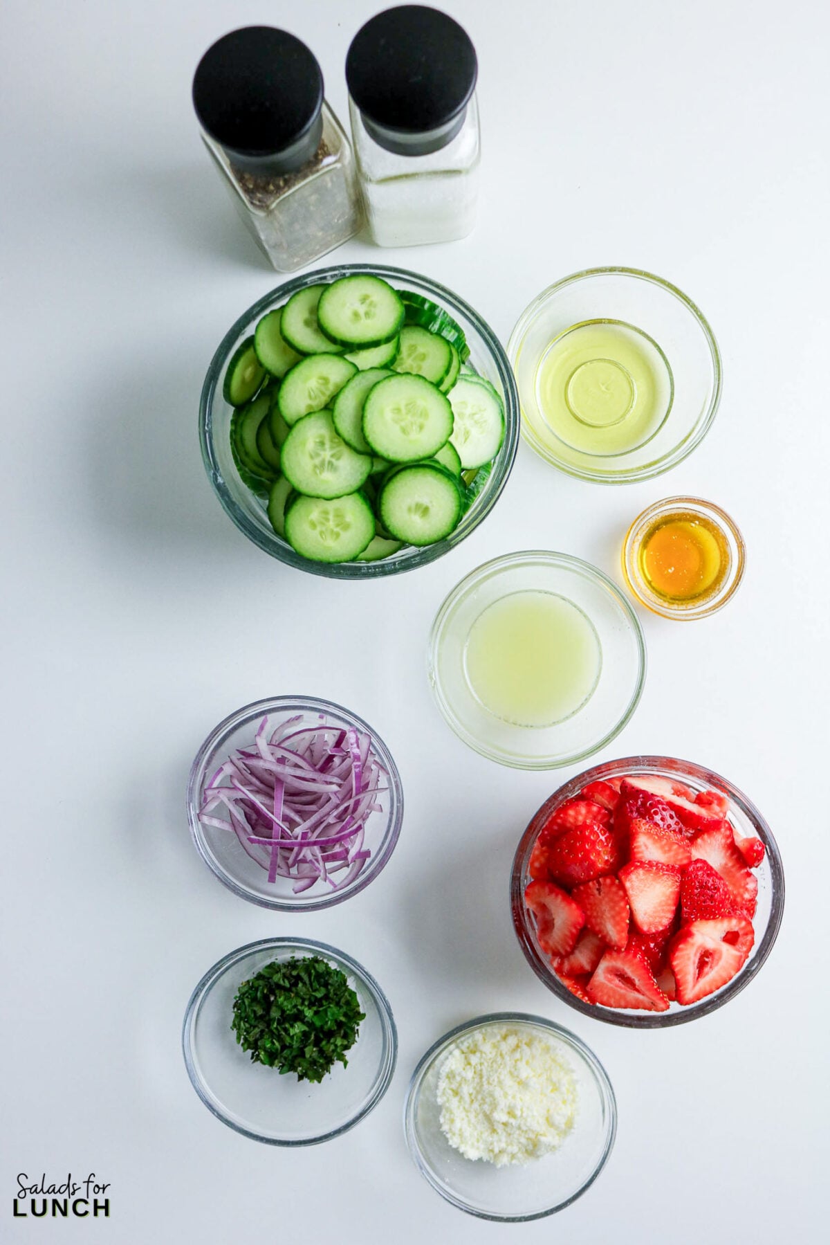 Strawberry Cucumber Salad ingredients: cucumbers, strawberries, feta, red onion, and dressing.