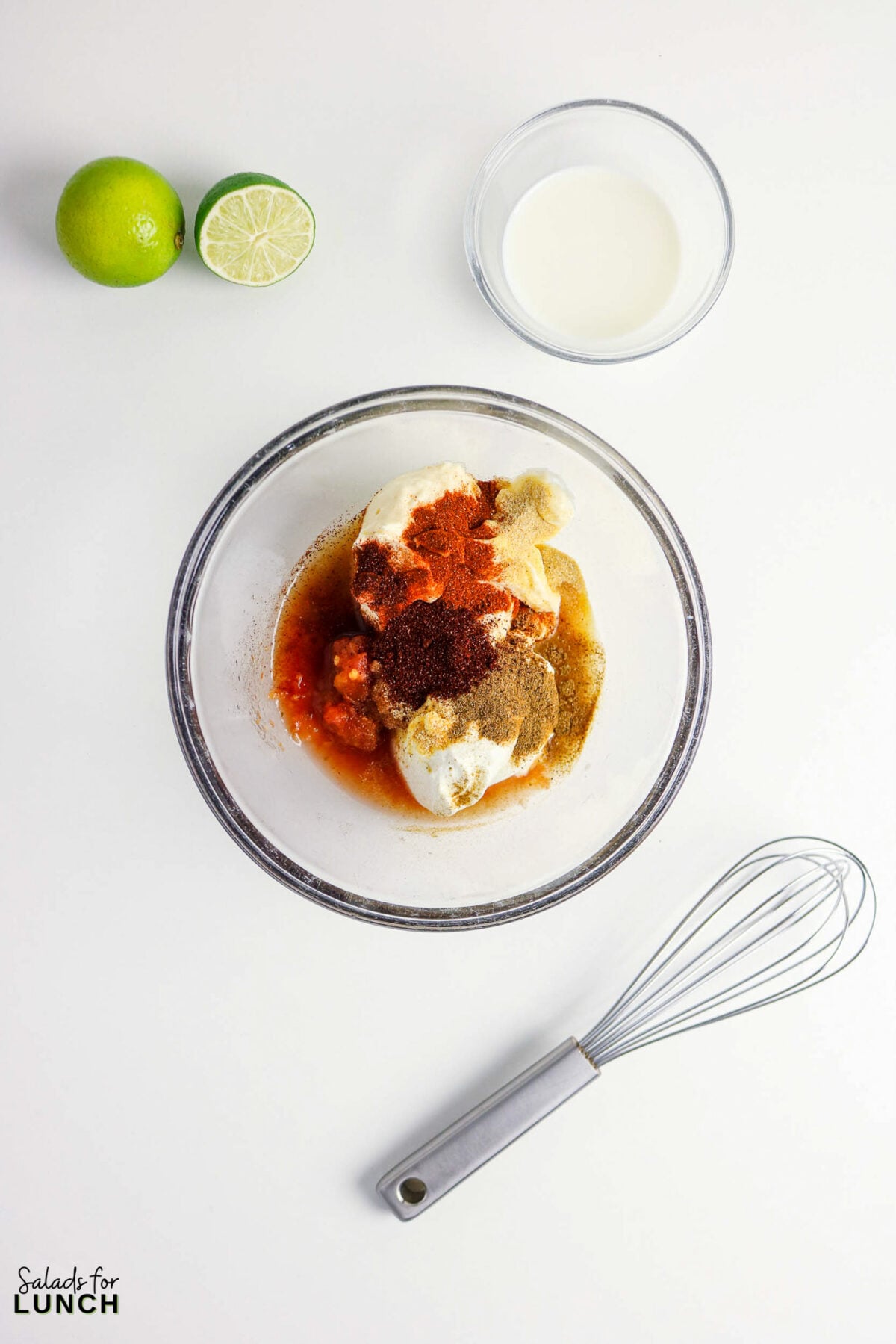 Ingredients for easy taco salad dressing in a glass bowl with limes and buttermilk.