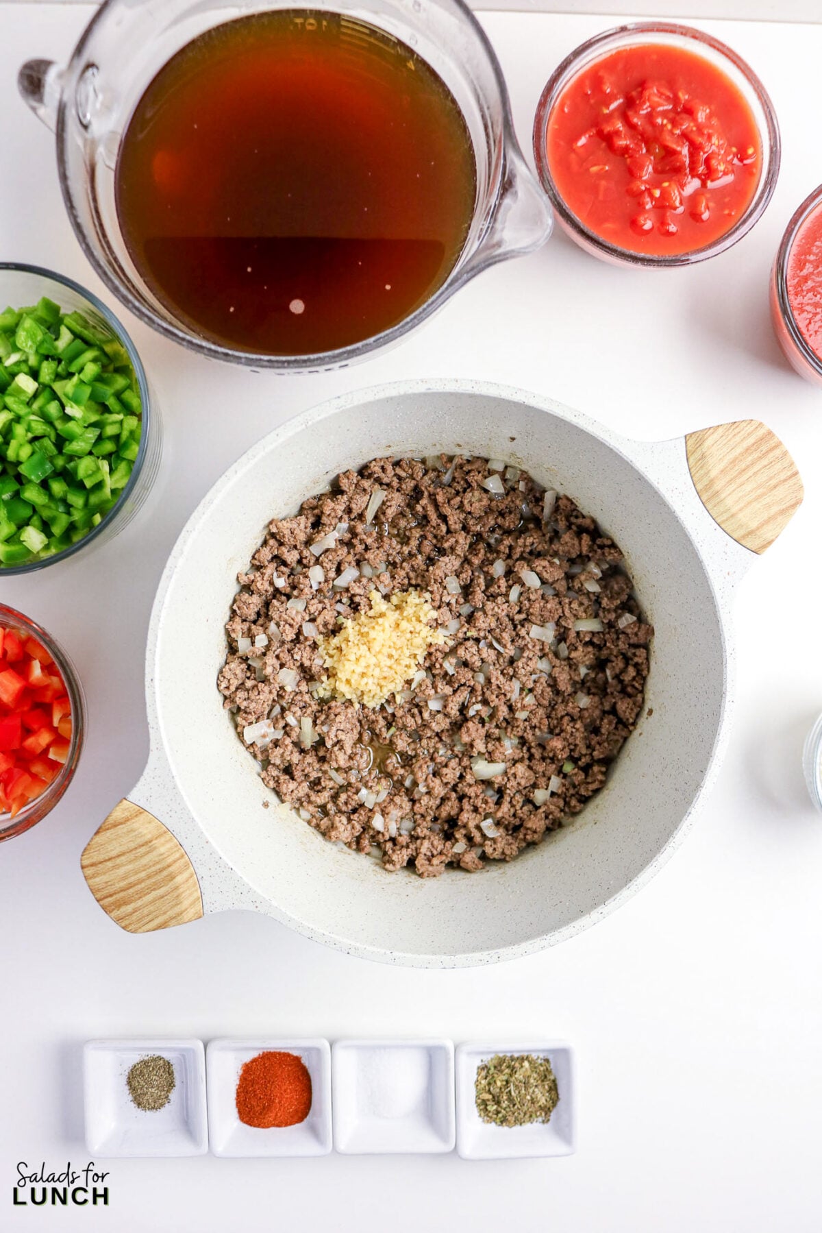 Ground beef, onions, and garlic in a pot with chili ingredients.