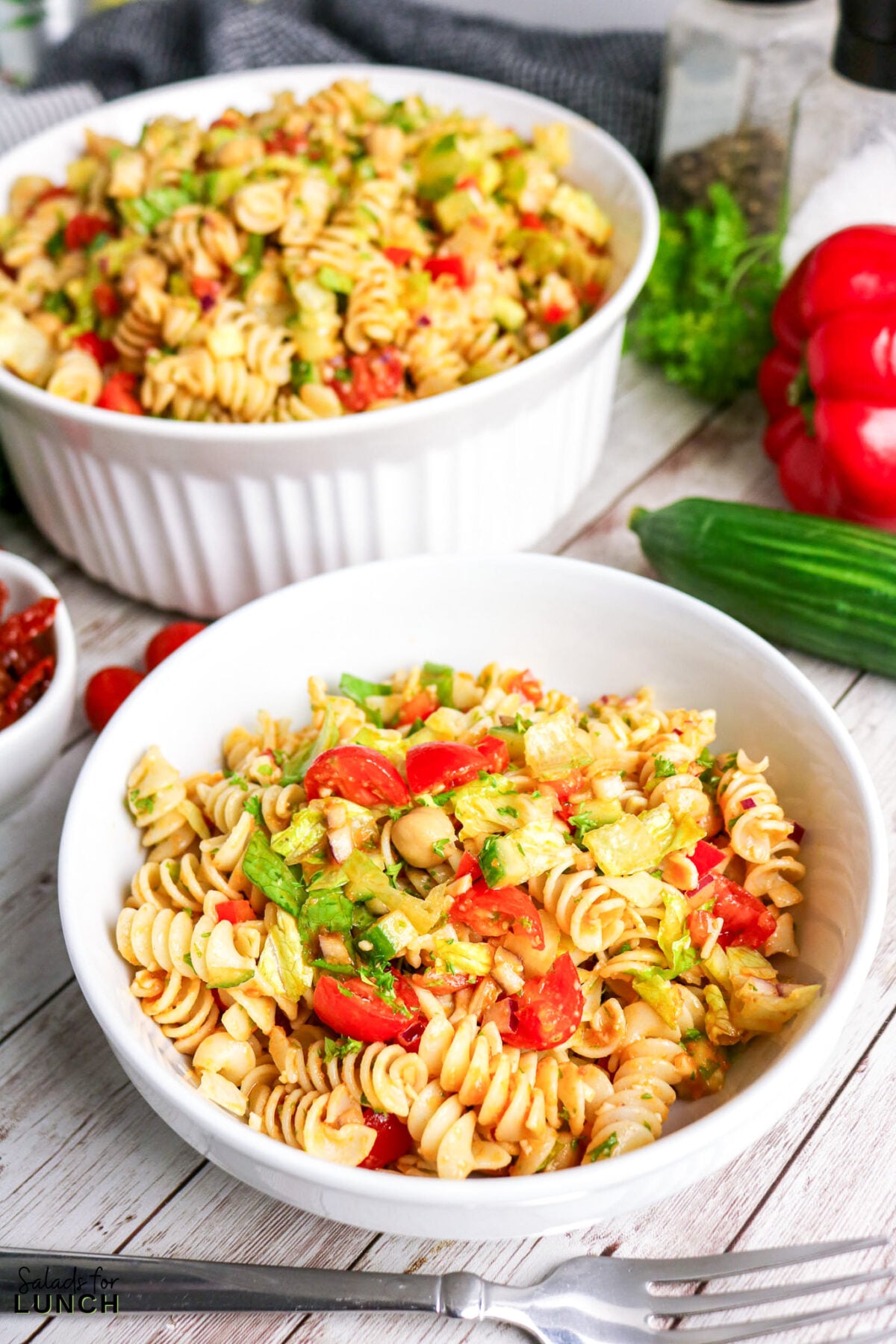 Pasta salad with tomatoes, cucumbers, and chickpeas in a white bowl