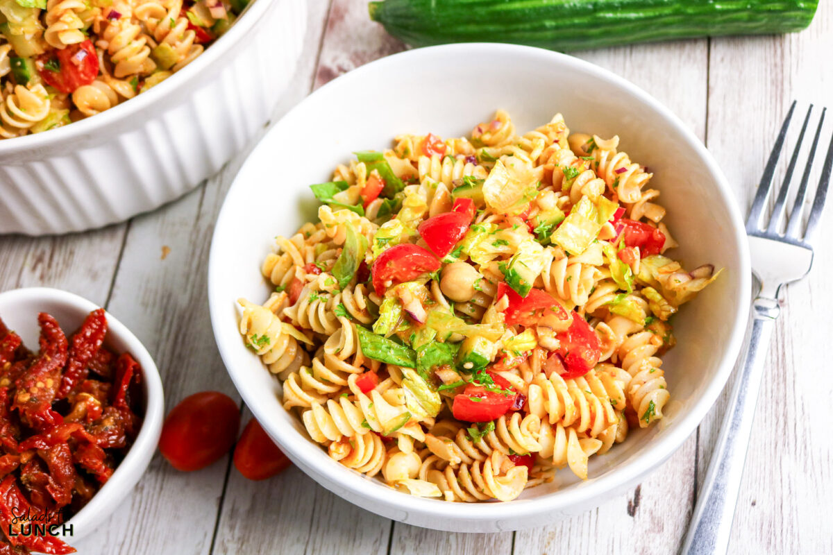 Easy Homemade Sun Dried Tomato Vinaigrette Dressing - pasta chickpea salad fresh Fresh pasta salad with tomatoes, chickpeas, lettuce, and cucumber in a white bowl.