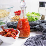 Pasta salad ingredients including sun-dried tomatoes, pasta, lettuce, and dressing.
