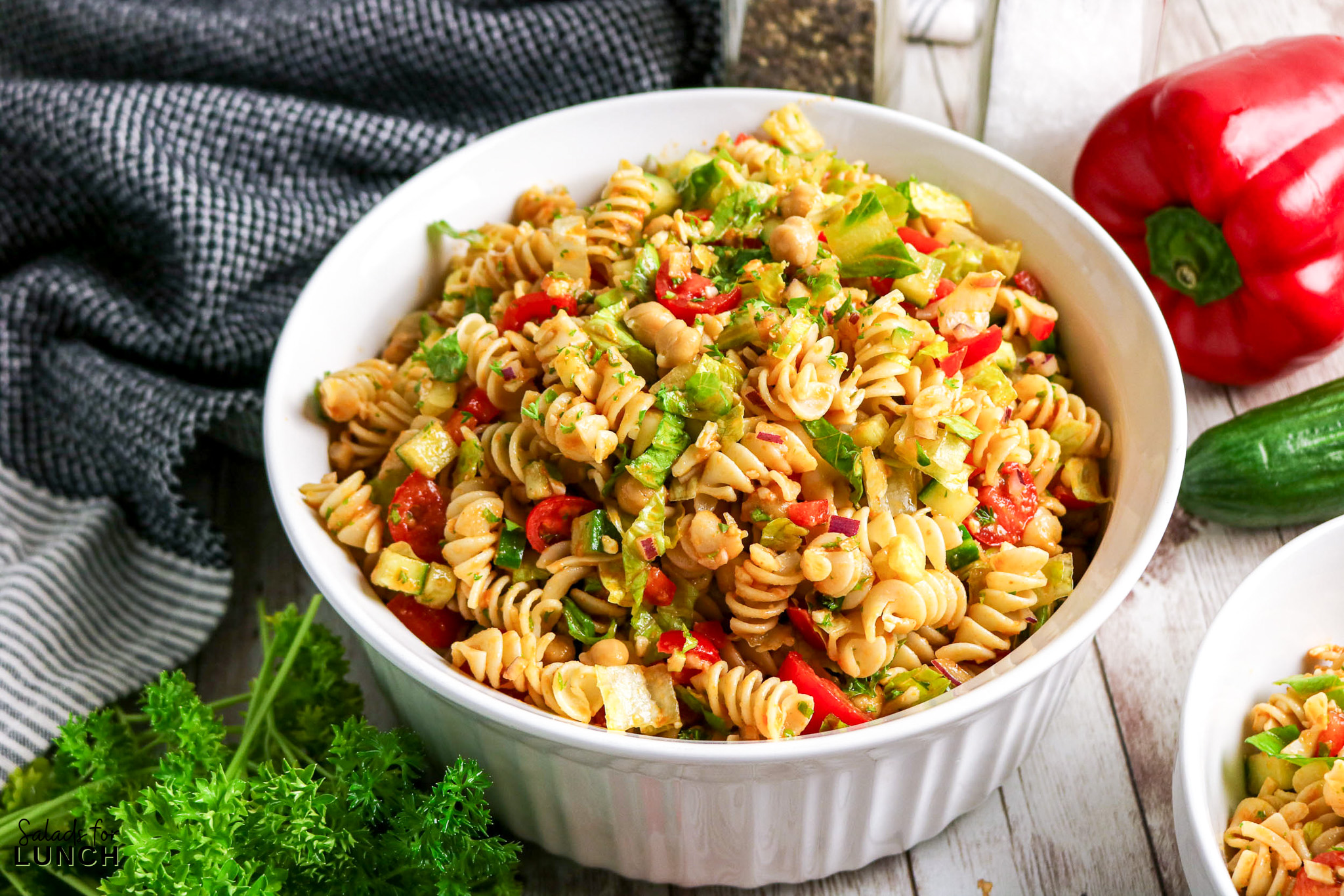 Healthy rotini pasta salad with chickpeas, cucumber, tomatoes, and red bell pepper.
