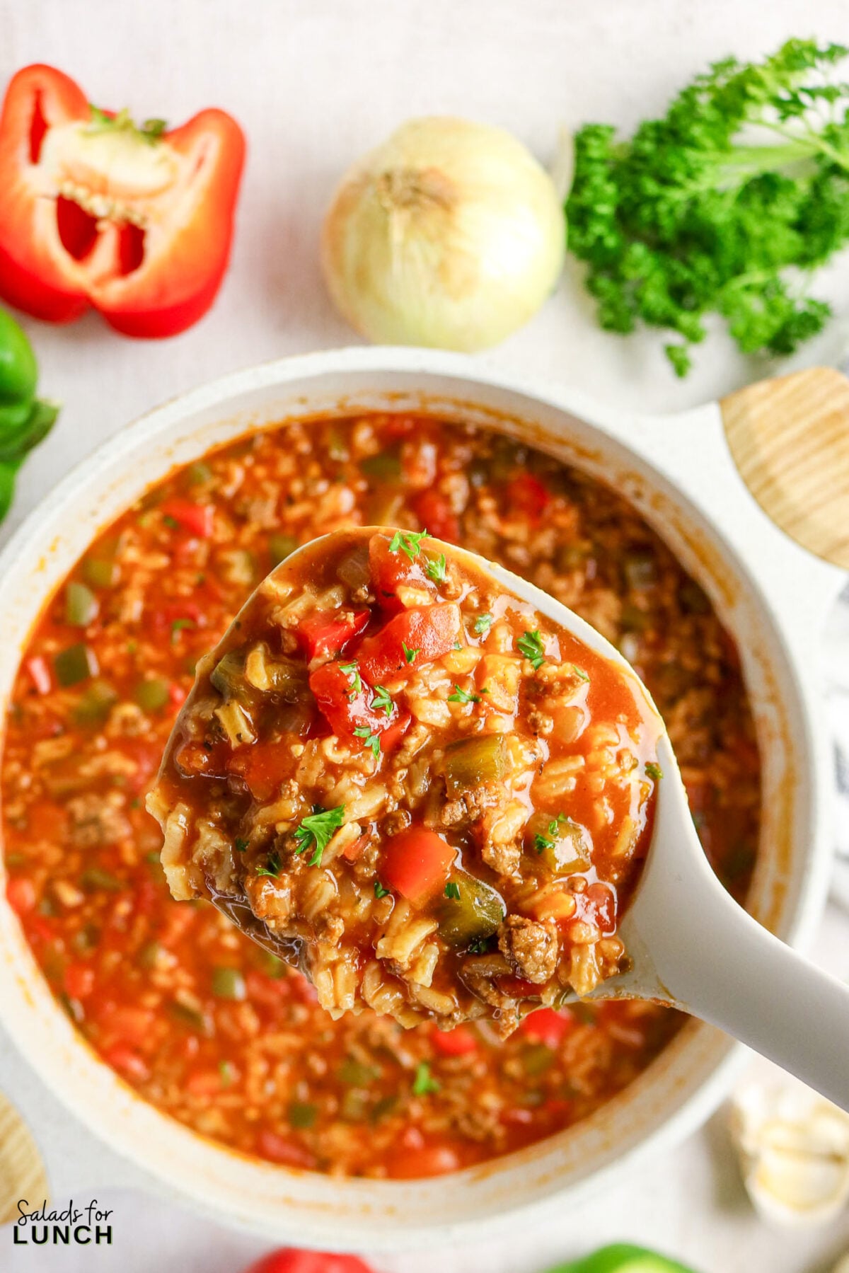 Stuffed pepper soup being served with peppers and onion in background.