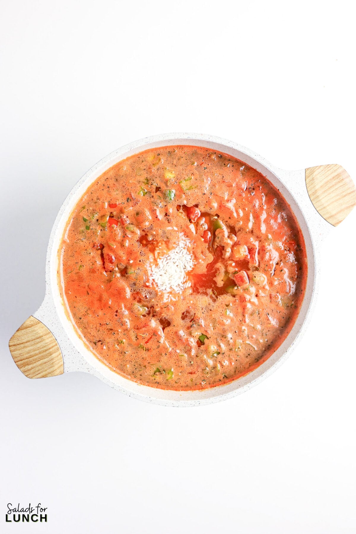 Pot of tomato-based soup with rice, ready to serve.