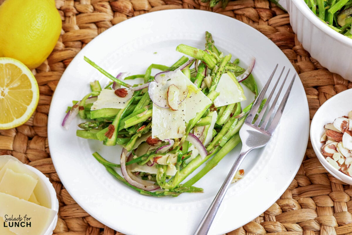 Shaved Asparagus Salad with Lemon Vinaigrette - asparagus parmesan salad almonds 1 Asparagus salad with shaved parmesan, red onion, and almonds on a white plate.