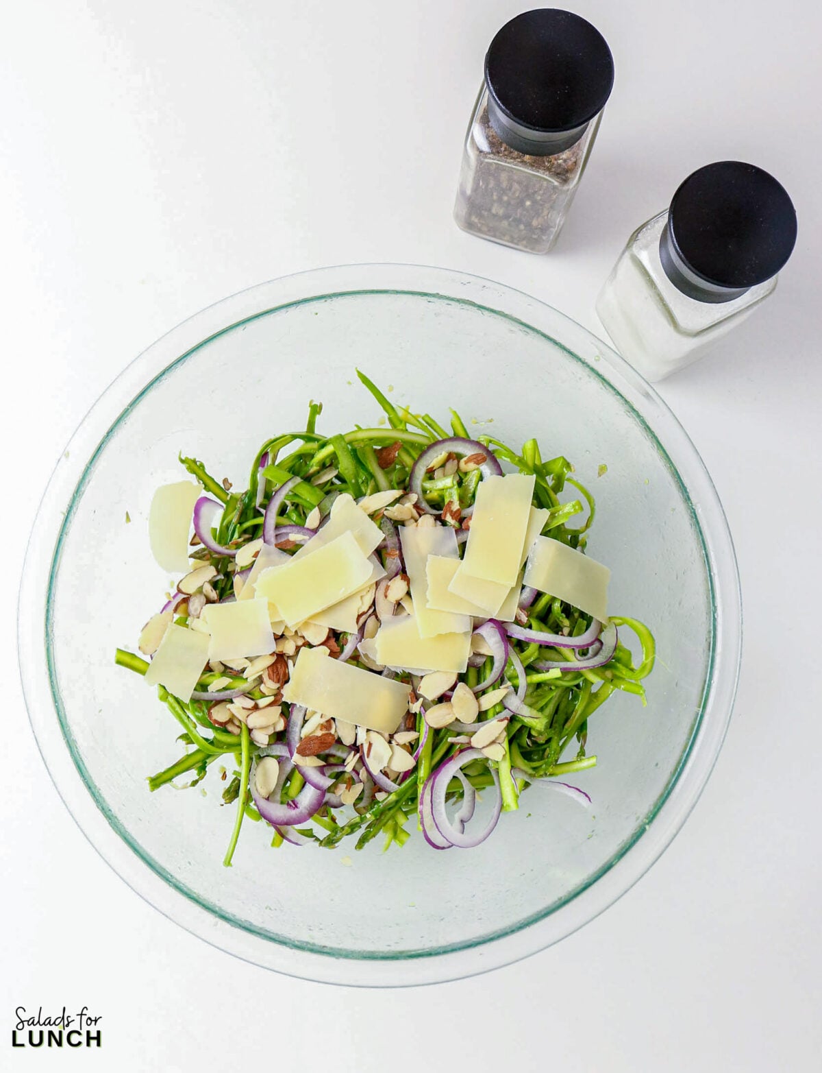 Shaved Asparagus Salad with Lemon Vinaigrette - asparagus ribbon salad parmesan almonds Asparagus ribbon salad with shaved parmesan and almonds in a glass bowl.