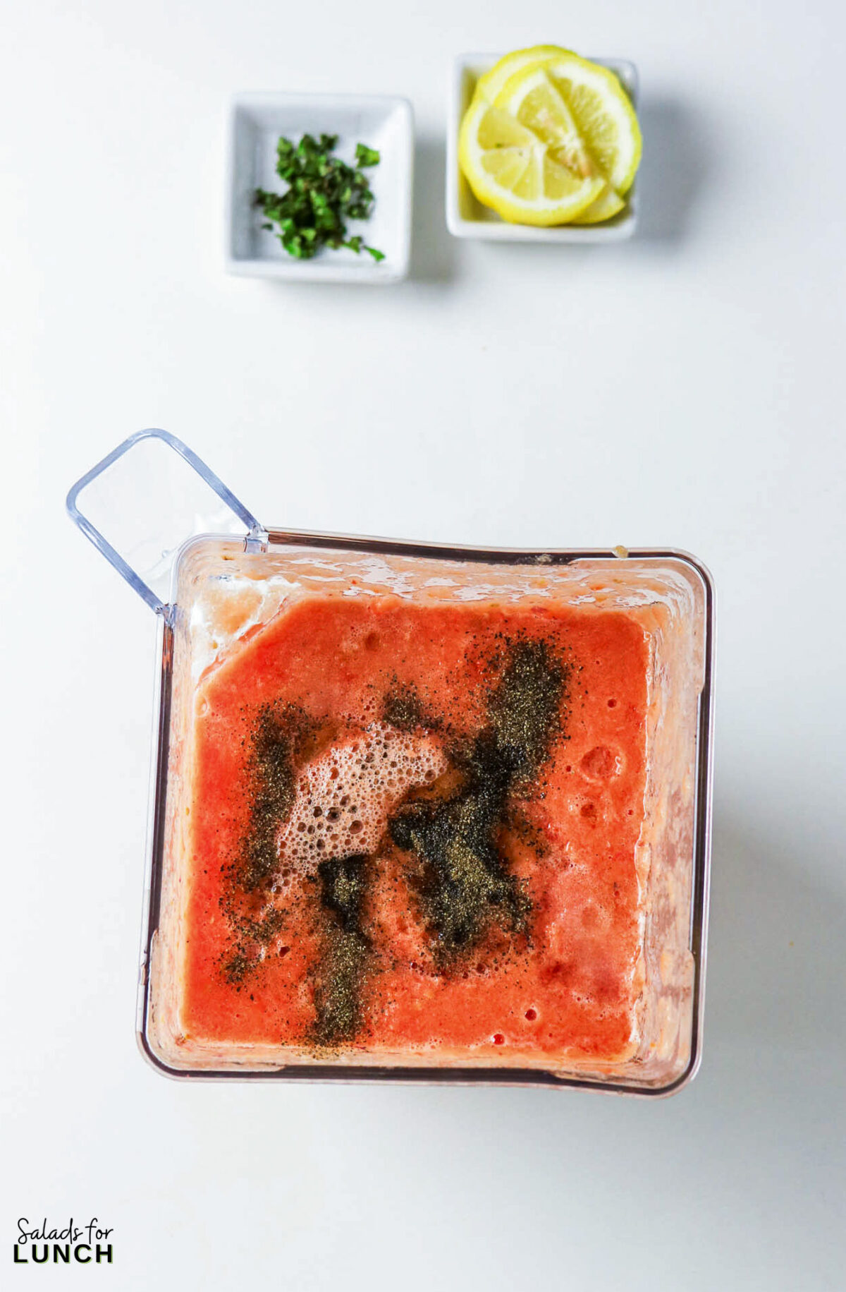 Blender with tomato mixture, pepper, and spices, plus lemon and herbs.