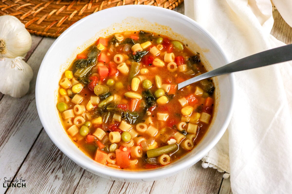 Soupe aux légumes facile dans un pot - Délicieuse soupe ditalini aux pâtes aux légumes 1 Délicieuse soupe de légumes aux pâtes ditalini dans un bol blanc, servie avec une cuillère.