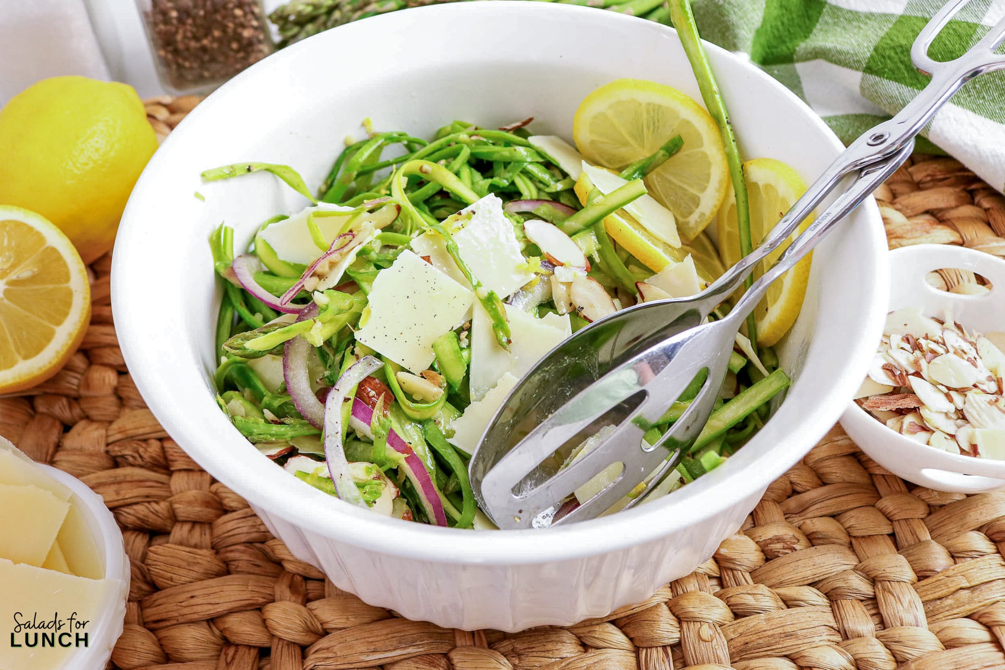 Shaved Asparagus Salad with Lemon Vinaigrette - shaved asparagus parmesan salad Shaved asparagus salad with parmesan, almonds, and lemon slices in a white bowl.