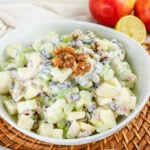 Apple Celery Walnut Salad with diced apples, celery, grapes, raisins, and walnuts in a creamy dressing, served in a white bowl.